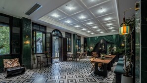 Une pièce dotée d’un sol à motifs géométriques, d’un coin repas avec une table et des chaises en bois, et d’un espace détente avec un canapé et des fauteuils.