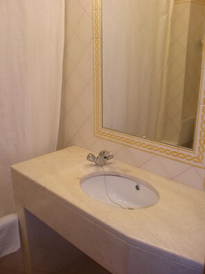 A bathroom with a sink, mirror, and tiled walls.