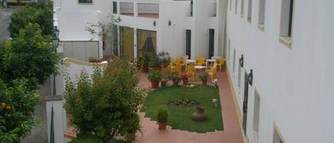 A courtyard with a paved walkway, potted plants, and outdoor seating.