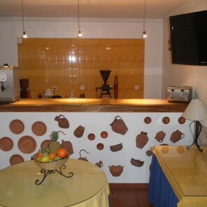 A kitchen with a tiled backsplash, a coffee machine, a toaster, and a fruit bowl on the table. - Hotel Passagem do Sol (Moura)