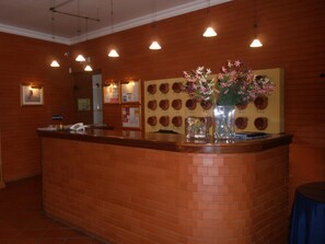 A reception area with a brick counter, a phone, and a wall with numbered plaques.