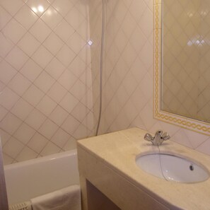 A bathroom with a white sink, a mirror with a decorative frame, and a bathtub. - Hotel Passagem Do Sol (Moura)