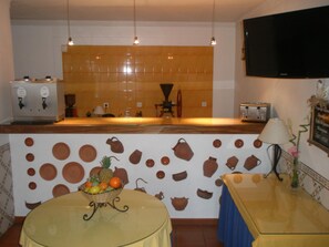 A kitchen with a tiled backsplash, a coffee machine, a toaster, and a fruit bowl on the counter. - Hotel Passagem Do Sol (Moura)