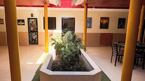 Un patio cubierto con un macetero central, pilares amarillos y suelo de baldosas.