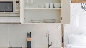Una cocina con microondas, lavamanos y armarios.