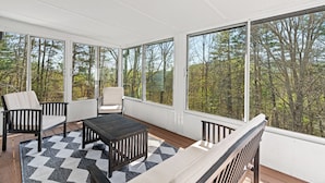 Una veranda con ampie finestre, un terrazzo in legno e mobili da esterno.