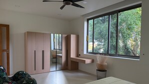 Ein Schlafzimmer mit einem Bett, einem Deckenventilator, einem großen Fenster und einem Kleiderschrank.