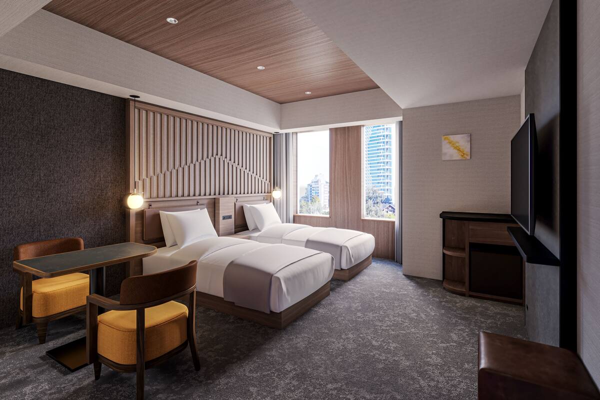 Habitación de hotel con dos camas, un escritorio, una silla, un televisor y vistas a la ciudad.