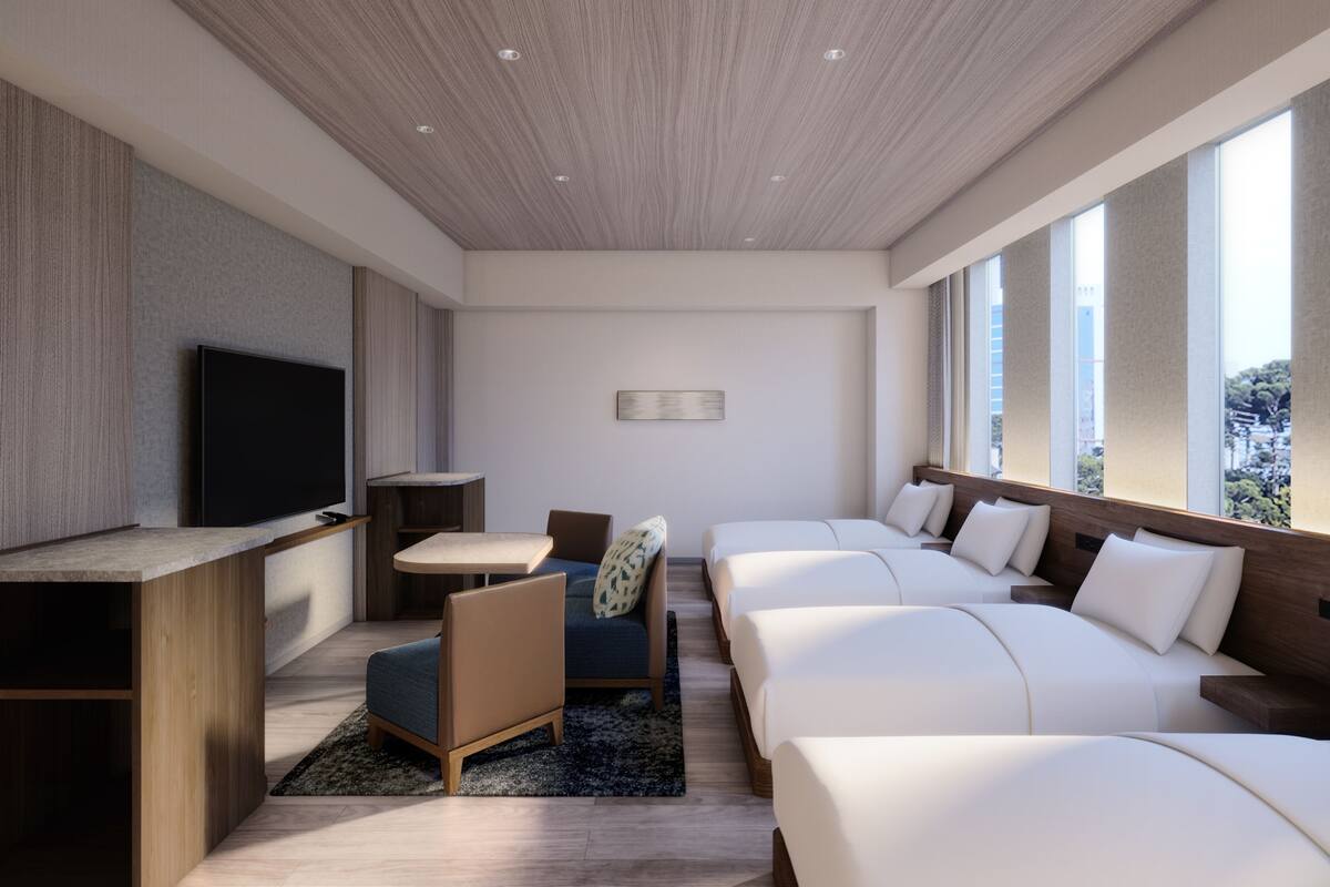Una habitación de hotel moderna con televisión de pantalla plana, un escritorio, un sofá, una cama y ventanas amplias.