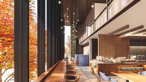 Un interior moderno con un largo banco de madera, una zona de bar y vistas a hojas otoñales a través de grandes ventanales.