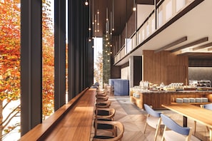 Um interior moderno com um longo banco de madeira, uma área de bar e vista para folhas de outono através de grandes janelas.