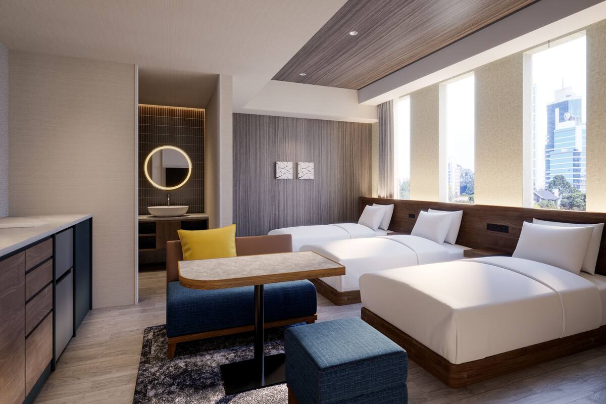 Habitación de hotel moderna con una cama grande, un escritorio, una zona de estar pequeña y vistas a la ciudad.