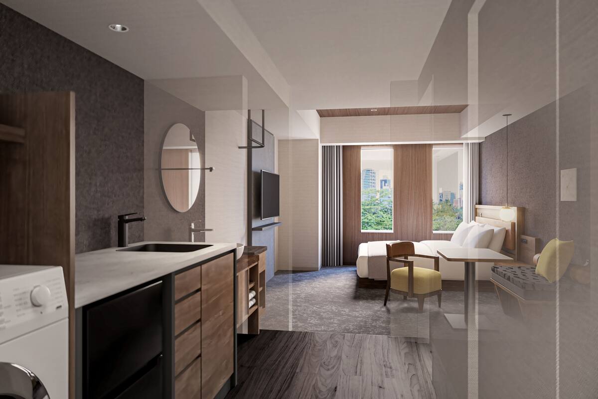 Una habitación de hotel moderna con una cama grande, un escritorio, una silla, un televisor y un baño con lavamanos y espejo.