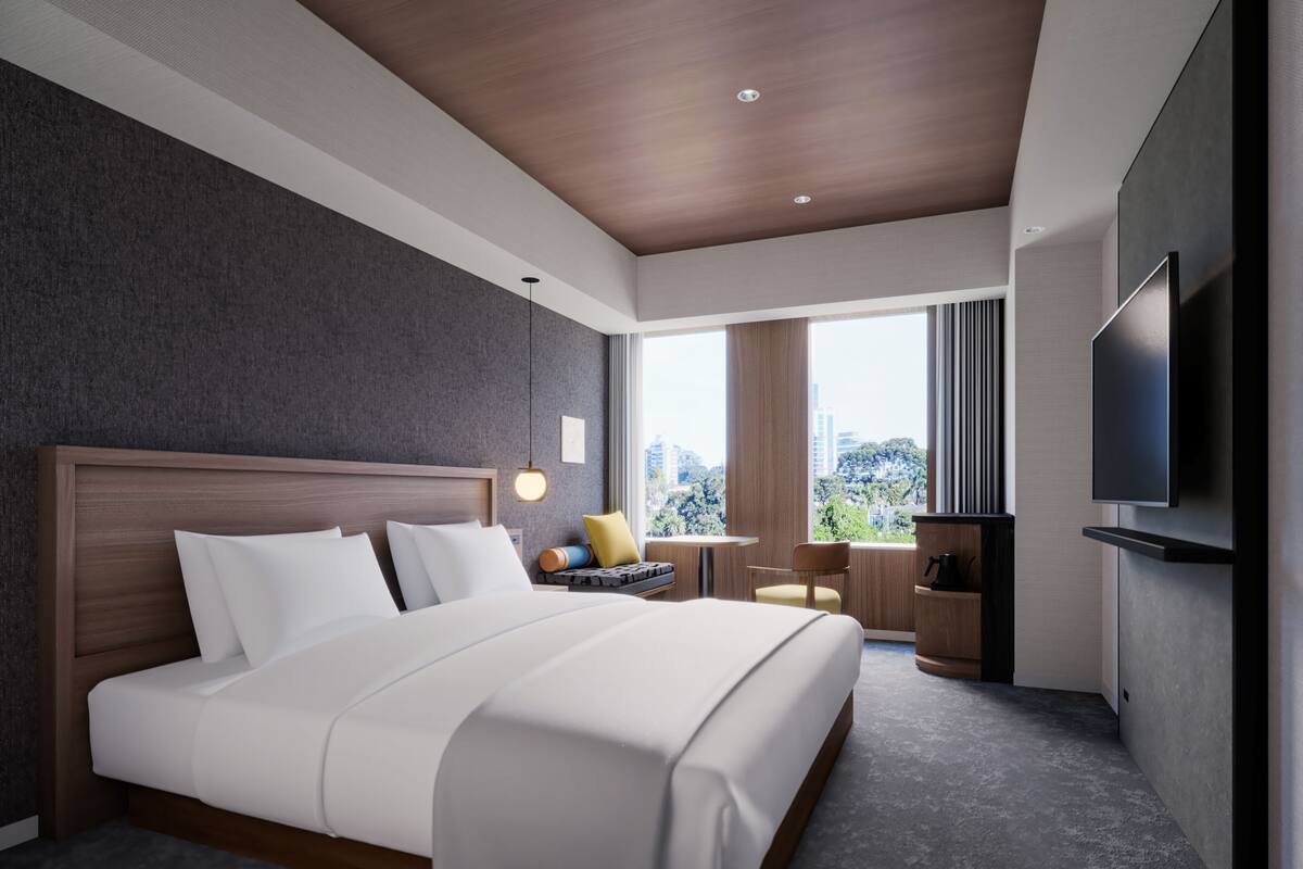 Habitación de hotel moderna con una cama grande, televisión, escritorio y vistas a la ciudad.