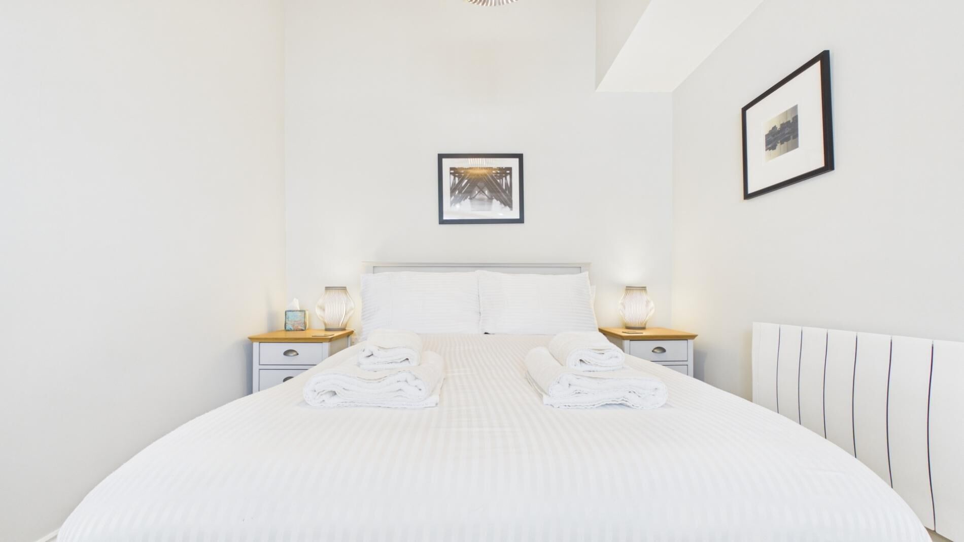 Een hotelkamer met een groot bed, twee nachtkastjes, een hoofdbord en twee wandlampen.