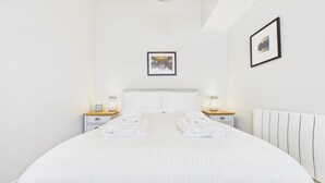 Een hotelkamer met een groot bed, twee nachtkastjes, een hoofdbord en twee wandlampen.