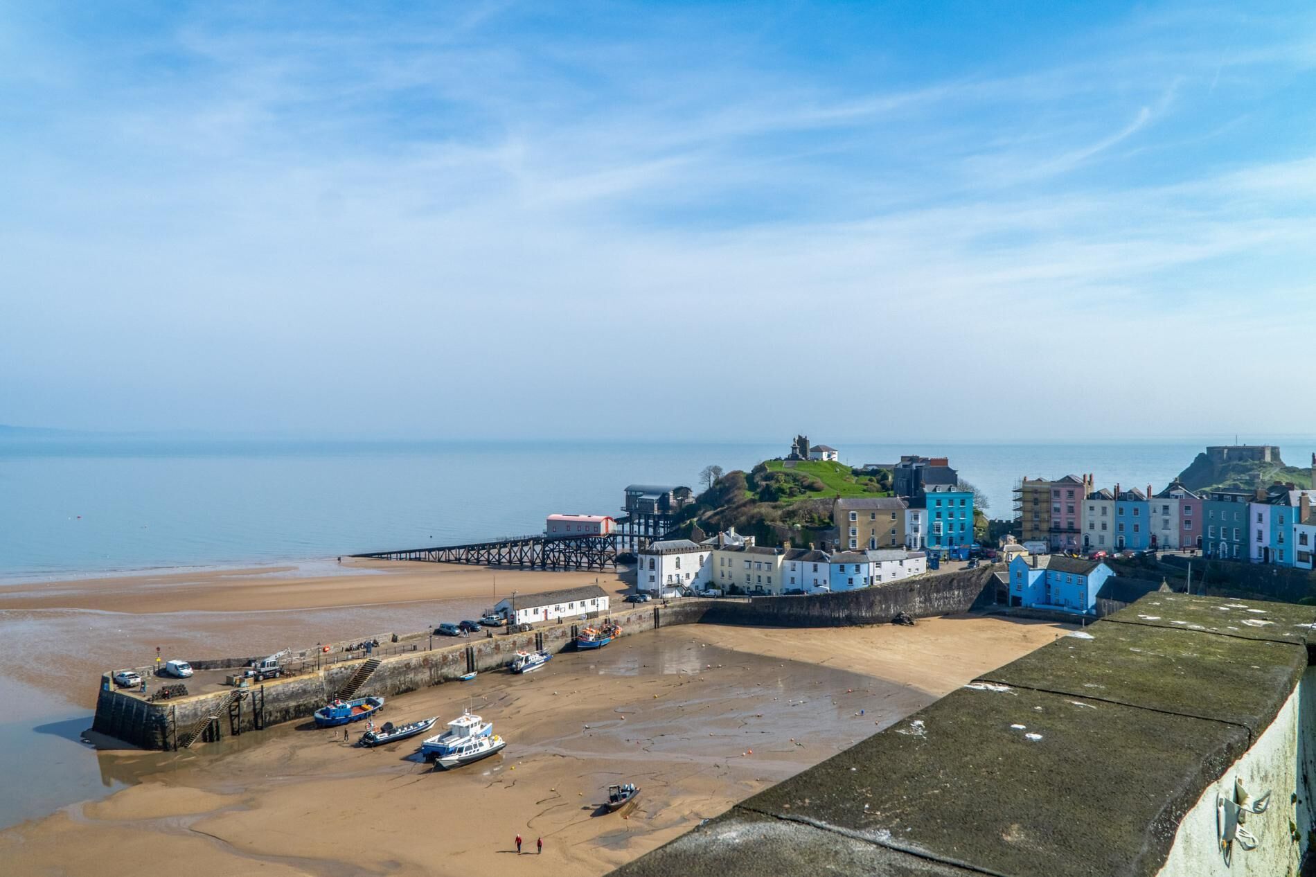 A coastal town with a pier, boats, and historic buildings.