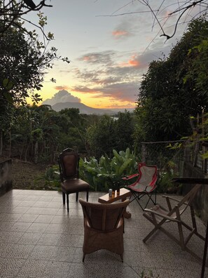 Un patio con sillas, una mesa y vistas al atardecer.