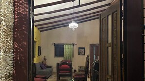 An interior view of a room with a tiled floor, a chandelier, a sofa, a chair, and a hat on the floor. - Quaint 1-bedroom country house in tranquil farm (Masaya)