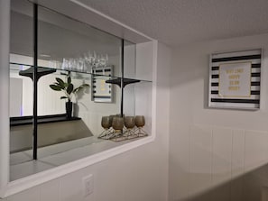 A kitchen with a glass shelf holding wine glasses and a potted plant. - Bright and cozy private suite near airport (Regina)
