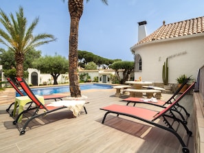 A poolside area with lounge chairs, a pool, and a building with a tiled roof. - Ref. PALMERA: Beautiful villa with 4 bedrooms, large private swimming pool and air conditioning (Escala (L'))