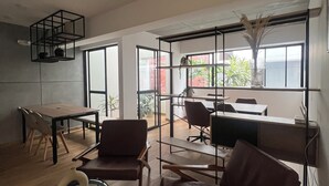 Ein modernes Interieur mit Essbereich, Sitzgelegenheiten und einem Arbeitsplatz mit großen Fenstern.