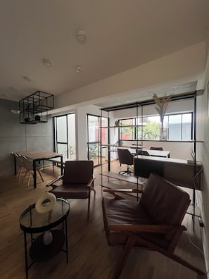 Ein modernes Interieur mit Essbereich, Sitzgelegenheiten und einem Arbeitsplatz mit großen Fenstern.