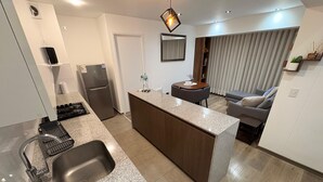 Eine moderne Küche mit Kochinsel, integrierten Geräten und einer Essecke mit Sofa und Tisch.