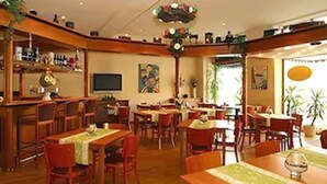 A restaurant with wooden furniture, a bar area, and a painting on the wall. - Hotel Schweizer-hof Baden Baden (Baden-Baden)