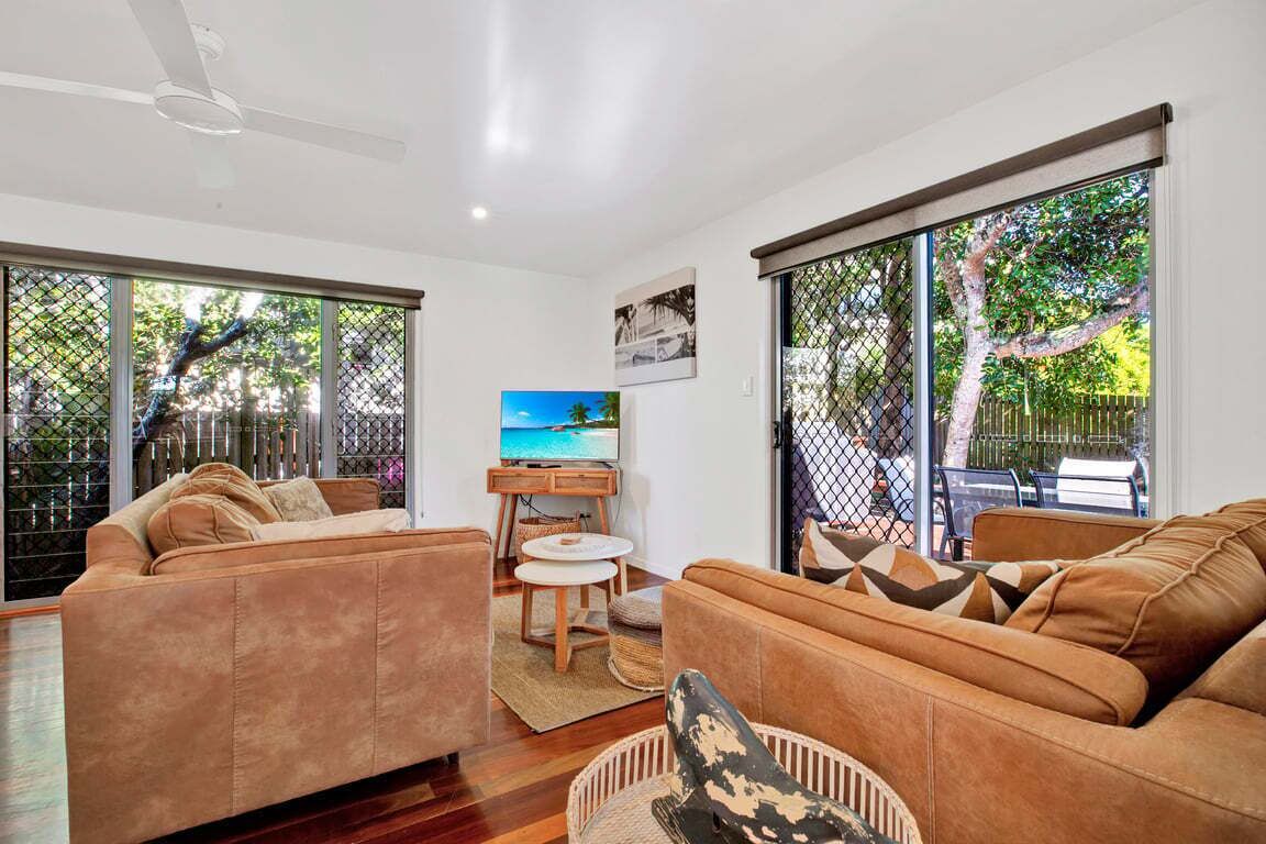 A modern living room with a sofa set, a television, and a dining area.