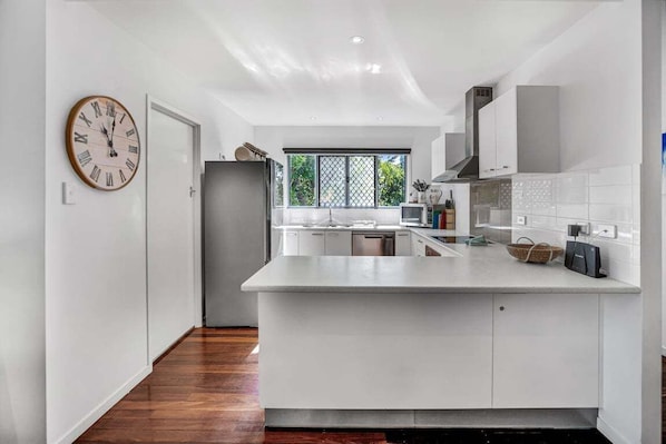 Una cocina moderna con armarios blancos, una isla grande y un reloj en la pared.