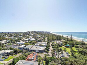 A coastal residential area with houses, a beach, and a clear sky.