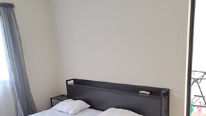 A single bed with a headboard, two pillows, and a bedside table in a room with a window and a door. - 2-bedroom bed & breakfast in charming Cancun with AC (Cancun)