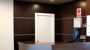 Um balcão de recepção com uma porta, uma máquina de café e um painel de controle na parede.