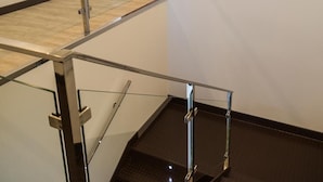 Um interior moderno com guarda-corpo de vidro, porta de madeira e escada.
