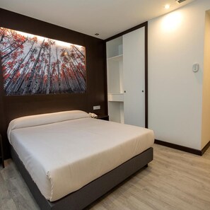 Un dormitorio moderno con una cama grande, un armario y una obra de arte colgada en la pared.