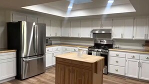 A modern kitchen with white cabinets, stainless steel appliances, and a wooden island. - Ranchito Robles, Hot Tub • Fire Pit • Wine Country Retreat (Paso Robles)