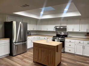 A modern kitchen with white cabinets, stainless steel appliances, and a wooden island. - Ranchito Robles, Hot Tub • Fire Pit • Wine Country Retreat (Paso Robles)