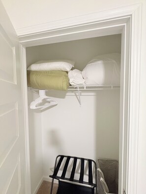 A closet with a hanging rack, shelves, and a folded chair. - Brand New 3-Bedroom/ 2.5 Bath - Townhome in West Midtown Atlanta (Atlanta)