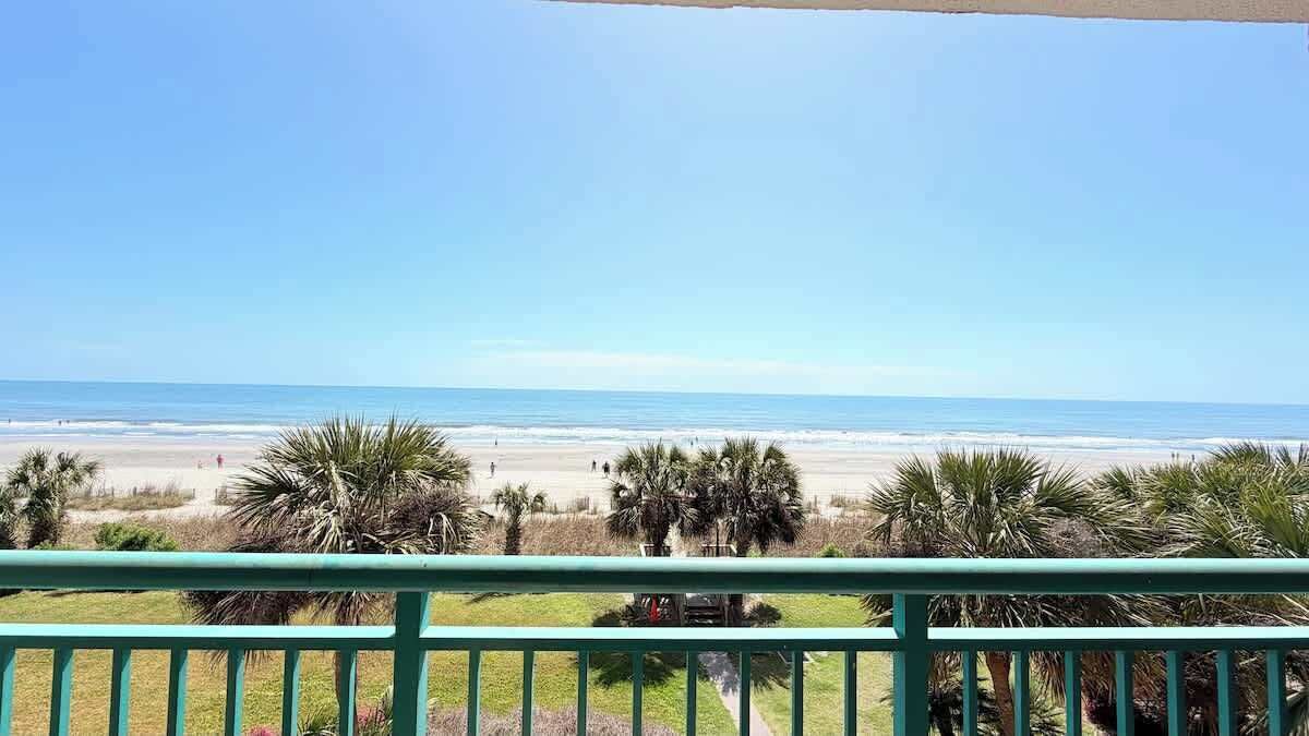 A balcony with a view of the beach and ocean.
