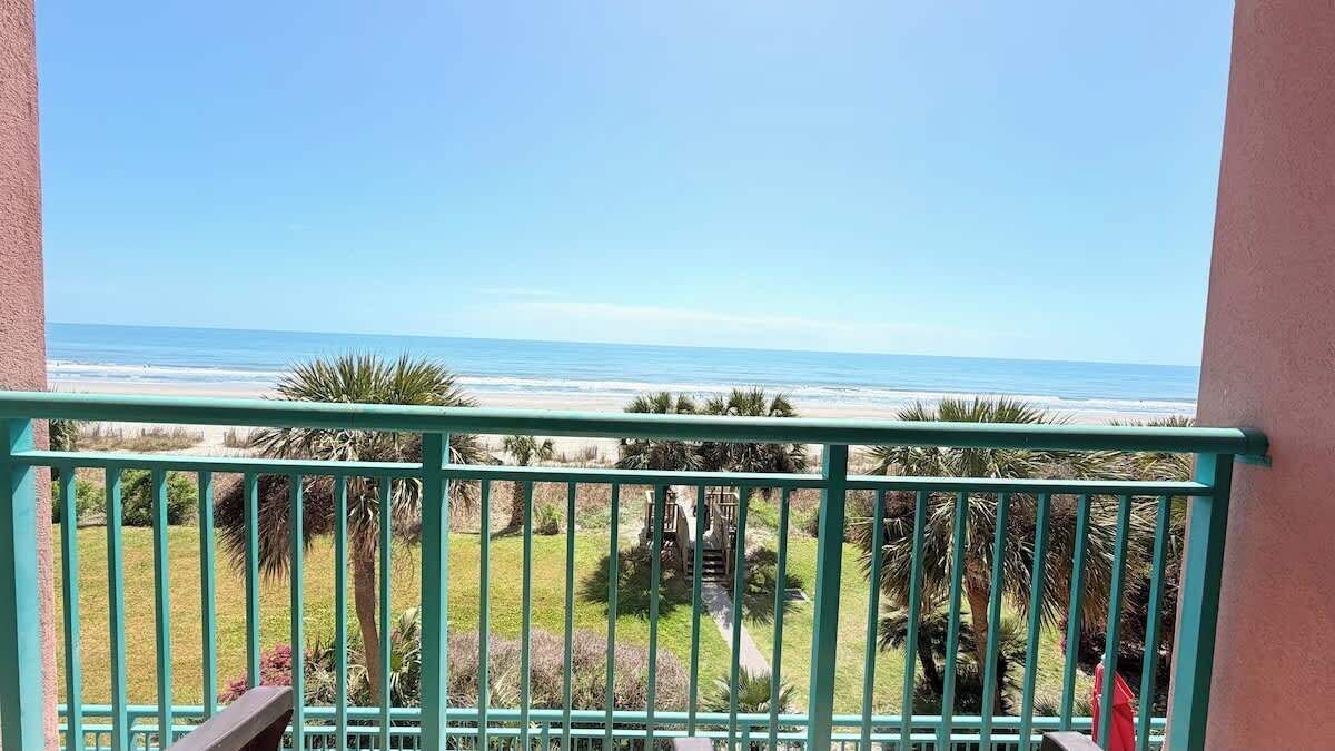 A balcony with a view of the beach and ocean.