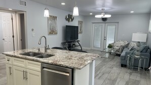 Una cucina moderna con piani di lavoro in granito, elettrodomestici in acciaio inossidabile e illuminazione a sospensione.