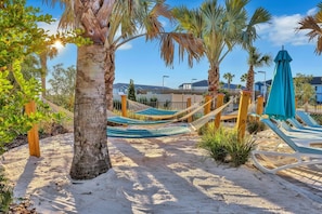 A sandy beach area with hammocks and lounge chairs, surrounded by palm trees and a clear sky. - 3811LNA 5 Bedroom Home (Davenport)