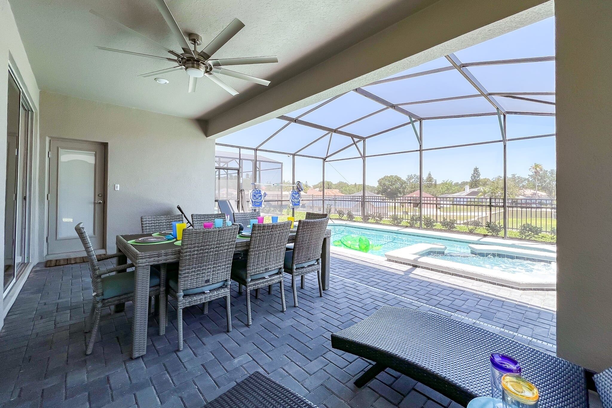 A covered patio with a table and chairs, a ceiling fan, and a view of a swimming pool.