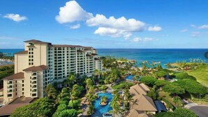 Un resort con un edificio grande, una piscina y vista al océano.