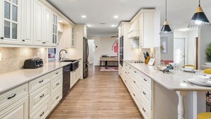 Une cuisine moderne avec des meubles blancs, un îlot central et des luminaires suspendus.