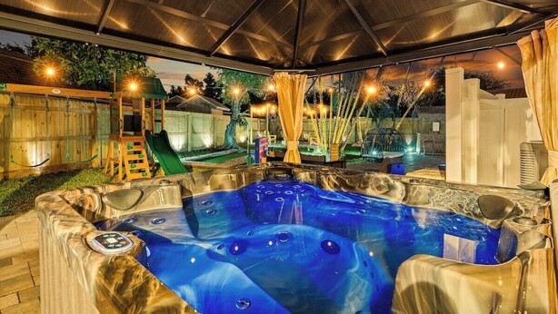 Un espace extérieur équipé d’un jacuzzi, doté d’un toit abrité, d’un toboggan et d’une clôture en bois.