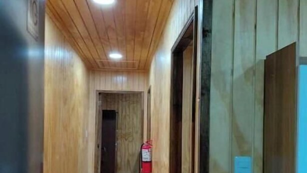 Un pasillo con paneles de madera y un extintor colgado en la pared.