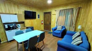 Un espacio habitable compacto con zona de comedor, kitchenette y sofá.
