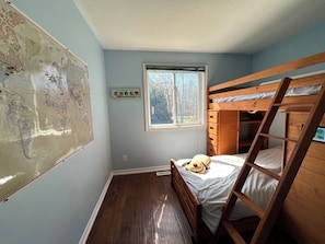 A room with a bunk bed, a window, a map on the wall, and a small shelf.